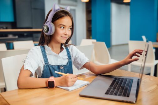 Pretty girl using a laptop computer at modern blue classroom. Pretty girl using a laptop computer at modern blue classroom.